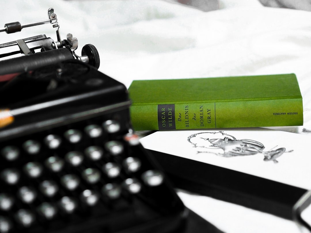 Still life of an antique typewriter, magnifying glass, ink pen and stacked mystery novels on a wooden desk